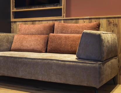 Gemütliche Sitzecke im Hotelzimmer mit gepolstertem Sofa, Fernseher und Holzboden.