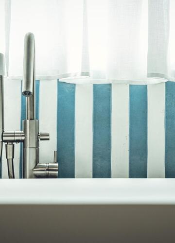 Detailansicht der Badewanne in der Suite Aura mit blau weißen Fliesen im Hintergrund.