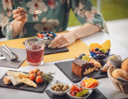 Woman sitting at a breakfast table set with sweet and savoury dishes.