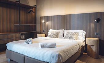 Zimmer mit Doppelbett, Wandleuchten und offenem Kleiderschrank im Hotel Villa Alberta.