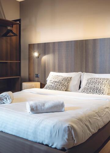 Zimmer mit Doppelbett, Wandleuchten und offenem Kleiderschrank im Hotel Villa Alberta.