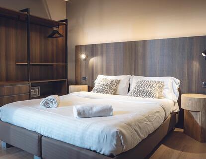 Zimmer mit Doppelbett, Wandleuchten und offenem Kleiderschrank im Hotel Villa Alberta.