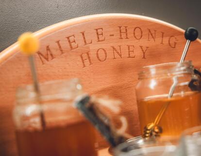Close-up of a honey station at a breakfast buffet, with liquid honey, honey dippers and jars.