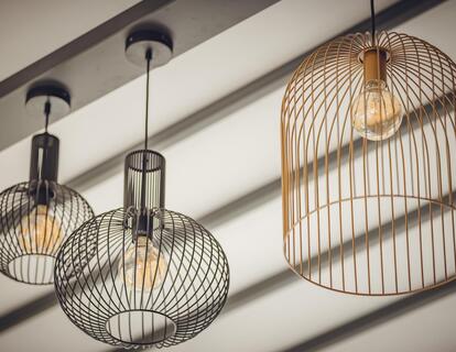 Lampade a sospensione decorative in rete metallica di diverse forme e dimensioni su un soffitto chiaro.