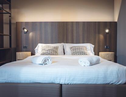 Zimmer mit Doppelbett, Wandleuchten und offenem Kleiderschrank im Hotel Villa Alberta.