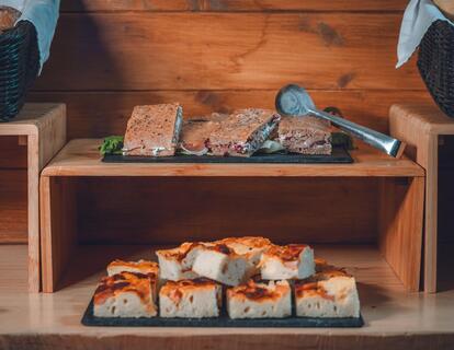 Breakfast buffet with savoury bread slices and topped appetisers on black serving platters.