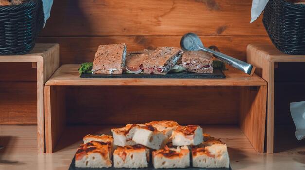 rühstücksbuffet mit herzhaften Brotschnitten und belegten Häppchen auf schwarzen Servierplatten.