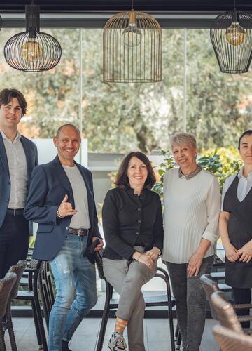 Das Team vom Hotel Villa Alberta vor einer Glasfront mit Blick in den Garten.