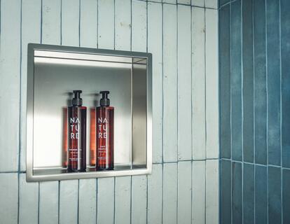 Piastrelle azzurre e blu scuro con nicchia per prodotti per la cura del corpo nella doccia della Suite Aura.