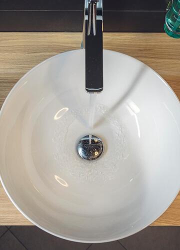 Detailaufnahme eines runden Waschbeckens auf einer Holzablage im Hotel Villa Alberta.
