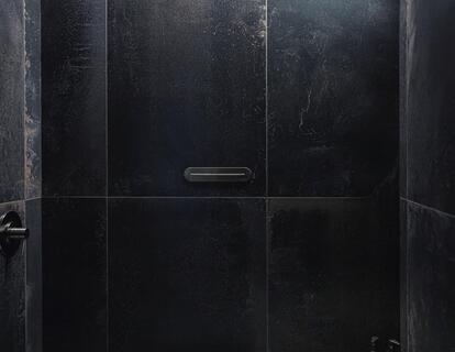 Moderne Dusche mit dunklen Steinfliesen und indirekter LED-Beleuchtung.
